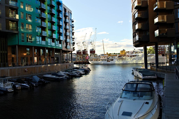 Oslo, Norvégia - Augusztus 29. 2020: Vízparti apartmanok egy csatorna a norvég királyi jacht a háttérben.  - Fotó, kép