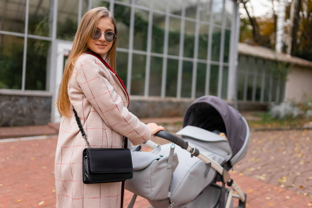 Portrait of stylish mother with baby stroller for a walk - Valokuva, kuva