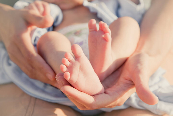 Πόδια μωρού στα χέρια της μητέρας. Η μαμά και το παιδί της. Χαρούμενη οικογενειακή ιδέα. Έννοια της μητρότητας. - Φωτογραφία, εικόνα