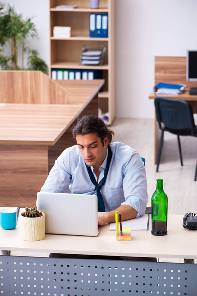 Young male employee drinking alcohol at workplace - Photo, Image