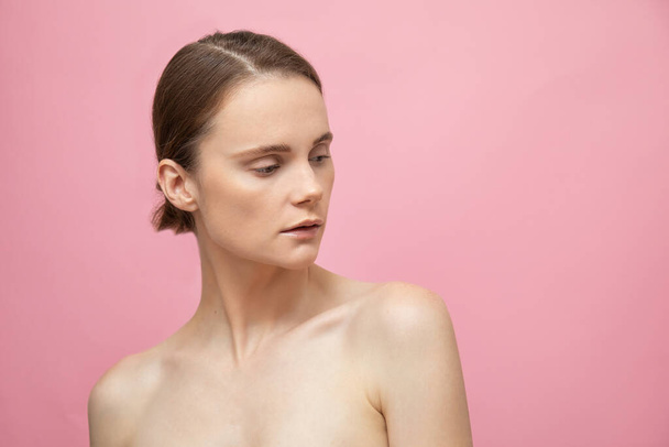 Beautiful sensual topless brunette woman standing isolated over pink background, posing. Happy female model. Human emotions and feelings. Nude makeup. Spa - 写真・画像