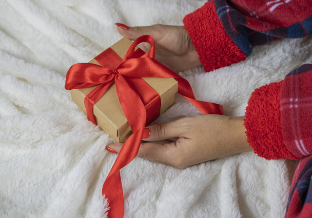 dziewczyna w piżamie Świętego Mikołaja trzymając pudełko z niespodzianką prezent z czerwonym łukiem na święta Bożego Narodzenia i Nowy Rok - Zdjęcie, obraz