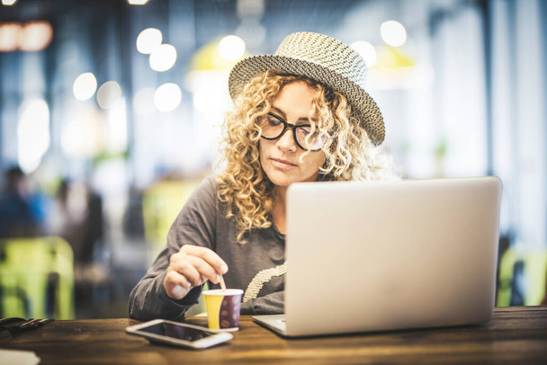 Bella giovane donna adulta al lavoro con computer portatile in un ristorante caffetteria in aeroporto in attesa del suo volo per viaggiare - Foto, immagini