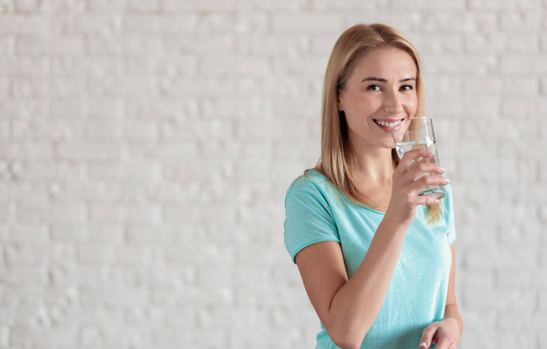 Portrait of happy smiling young woman with glass of fresh water. Healthy lifestyle concept - Foto, immagini