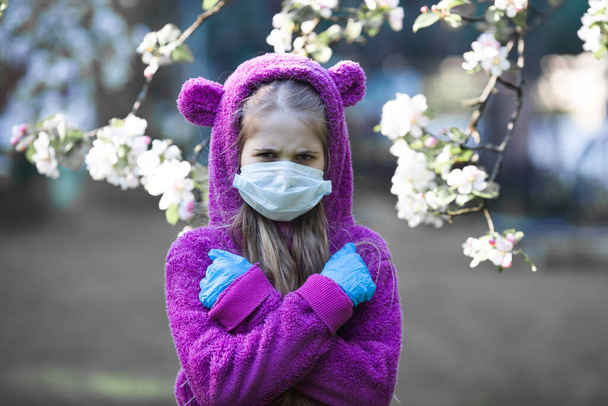 Mutsuz sarışın kız lateks koruyucu eldiven takıyor ve maske takıyor çiçek koklayamıyor. Yeni koku kaybı - COVID-19 'un en önemli belirtisi. Ellerini çapraz yapıp Coronavirus karantinasını protesto eden bir kız.. - Fotoğraf, Görsel