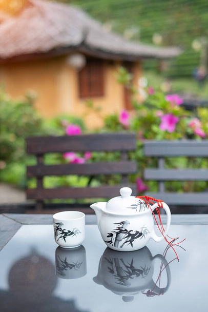 teáskanna és forró tea csésze fa asztal ellen tea kert kilátás háttér reggel, Ban Rak Thai falu, Mae Hong Son tartomány, Thaiföld - Fotó, kép