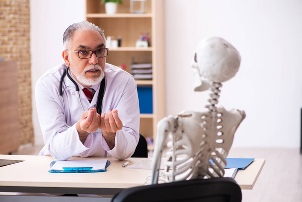 Old male doctor and skeleton patient in the clinic - Фото, зображення