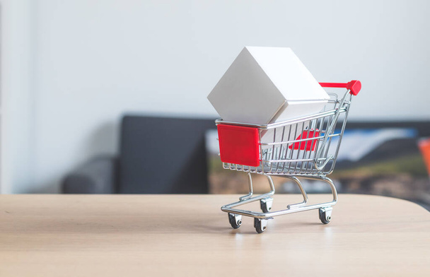 Online-Shopping and parcel service concept: Miniature shopping cart and white box - Fotó, kép