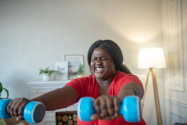 Plus size african american woman doing squats with dumbbells with tension - Fotoğraf, Görsel