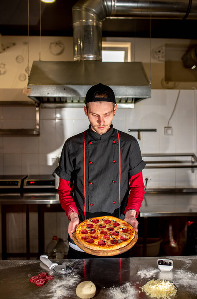 view of chef showing fresh pizza at kitchen, cooking concept - 写真・画像
