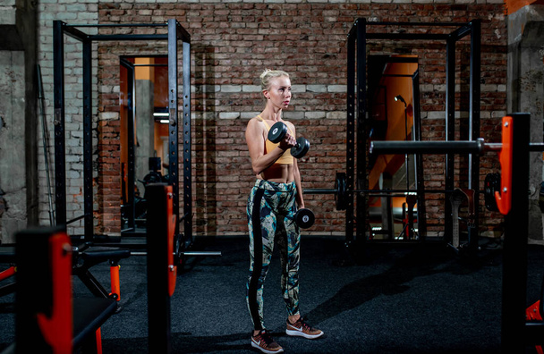 donna con corpo muscolare che fa esercizio fisico pesante in palestra - Foto, immagini