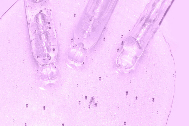 close up macro of pipette dropper with liquid with particles on a purple background - Photo, Image