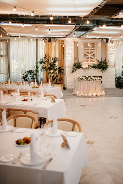 o presidium dos recém-casados no salão de banquetes do restaurante é decorado com velas e plantas verdes, o tom geral do salão é bege - Foto, Imagem