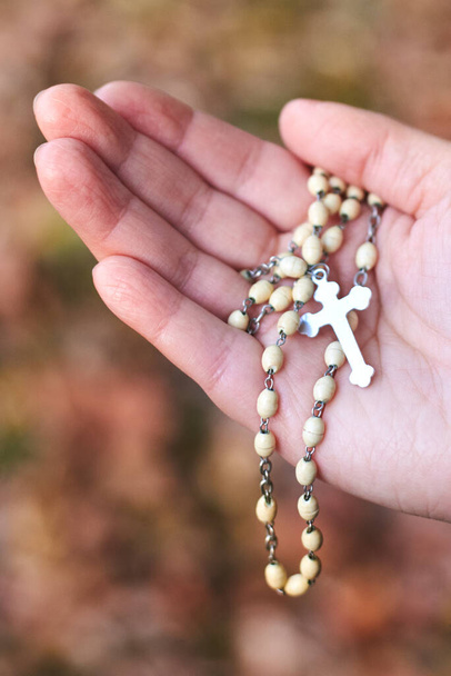 Le mani delle donne che tengono il rosario sullo sfondo autunnale, primo piano. - Foto, immagini