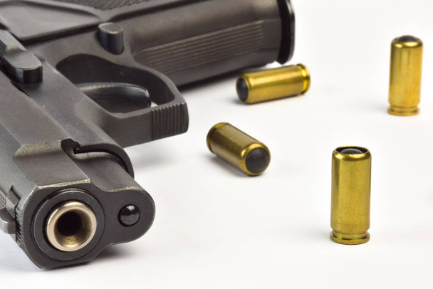 Pistolet traumatique avec canon dans le cadre close-up et plusieurs cartouches sur fond de clipsage blanc - Photo, image