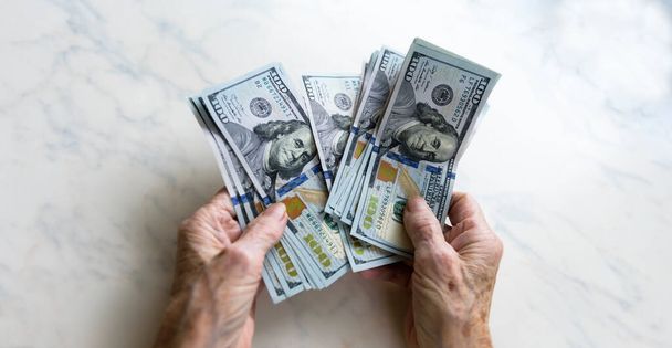 Zbliżenie rąk starszych kobiet trzymających pieniądze w banknotach 100-dolarowych - Zdjęcie, obraz