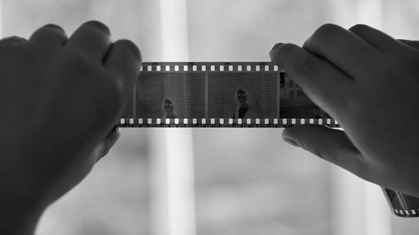 Una mujer sostiene un negativo de una vieja cámara de cine, primer plano, foto en blanco y negro. - Foto, Imagen