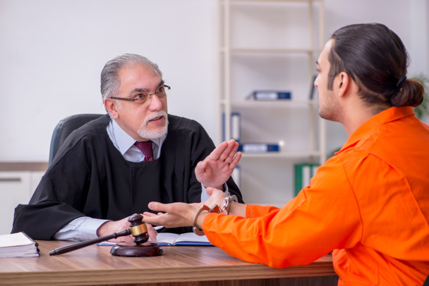 Alter männlicher Richter trifft junge Gefangene im Gerichtsgebäude - Foto, Bild