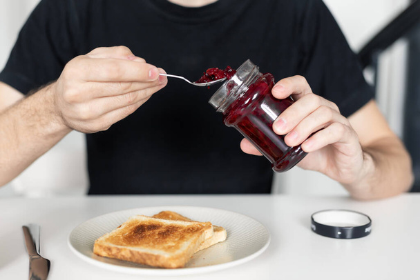 The guy has breakfast with toast with jam - Фото, зображення