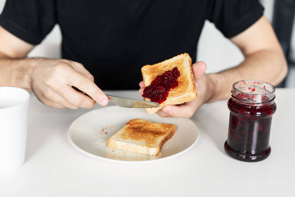 The guy has breakfast with toast with jam - Valokuva, kuva