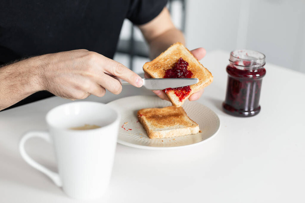 The guy has breakfast with toast with jam - Zdjęcie, obraz