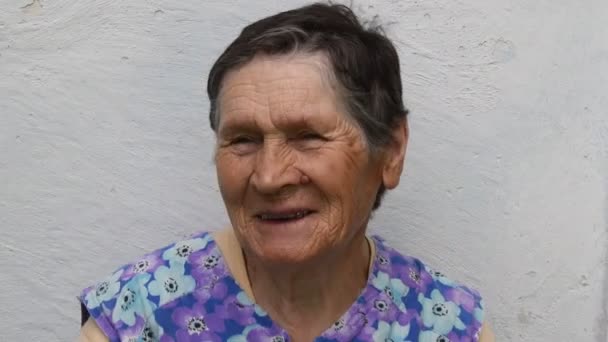 Portret van een glimlachende oudere vrouw die haar grijze haar aanraakt om haar korte kapsel glad te strijken - Video