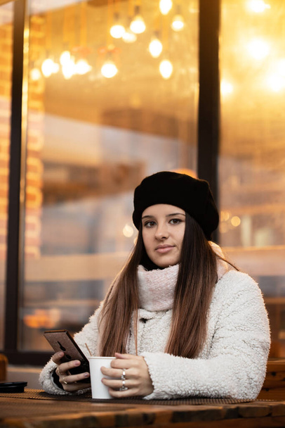 Jeune fille buvant du café pendant qu'elle parle sur son téléphone. Fille Boire du café dans un restaurant confortable. - Photo, image