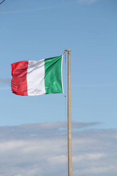 Italian flag waving against the sky, hung on a cement pole, three colors - Foto, afbeelding