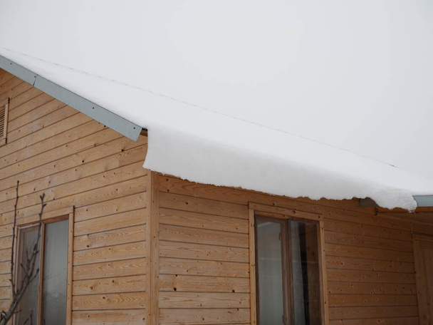 Παγωμένο φράγμα στην οροφή. Shingle στέγη στο σπίτι με icicles και φράγμα πάγου ξεκινά μια διαρροή στην οροφή. - Φωτογραφία, εικόνα