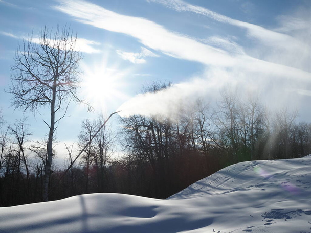 Kar topu. Kayak merkezinde kar yağdırıcı arka planda dağlar olan yapay kar püskürtüyor. Işığa yansıyan kar daha parlak bir etki yaratır. Kış yarışması - Fotoğraf, Görsel