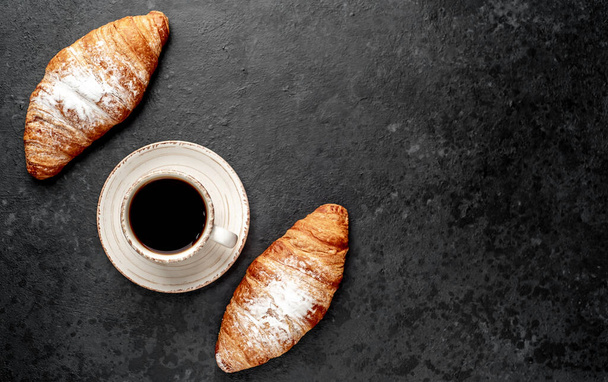 vrchní pohled na čerstvé croissant a černá káva na šedém pozadí  - Fotografie, Obrázek