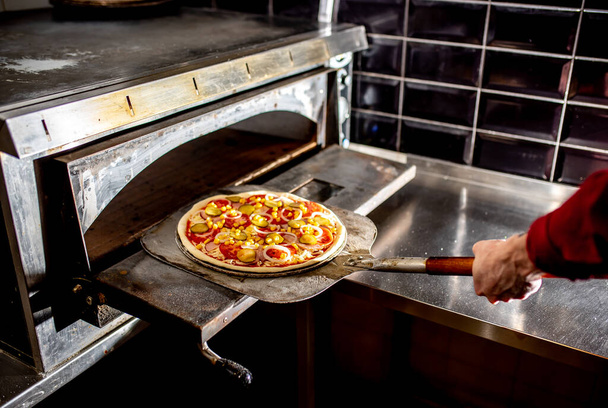 zbliżenie kucharz podejmowania pizzy w kuchni, koncepcja gotowania  - Zdjęcie, obraz
