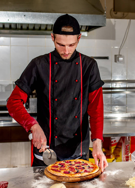 вид на шеф-кухаря, що ріже свіжу піцу на кухні, концепція приготування
 - Фото, зображення