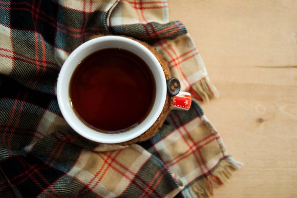 Зима, осінній фон. Чашка гарячого чаю, одягнена в в'язаний теплий зимовий шарф на дерев'яному фоні
. - Фото, зображення
