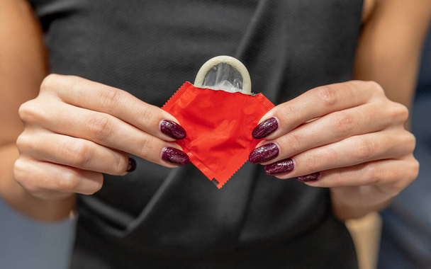 Femme tient un préservatif dans ses mains - Photo, image