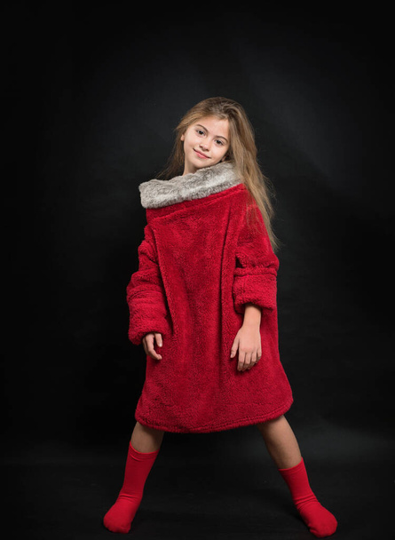 Teenage girl in a red fur coat in the studio on a black background. - Foto, Imagen