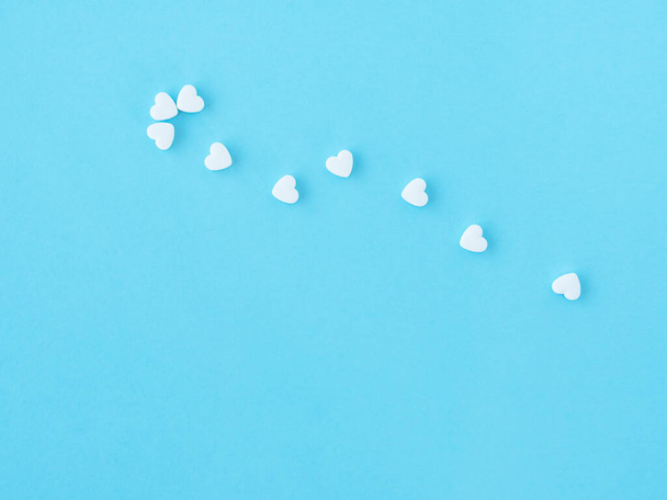 Pharmaceutical and cardiology concept. White medical cardiological pills in the form of heart on blue background. Minimalism style template for medical blog. Cope space for text. Pills of love - Фото, изображение