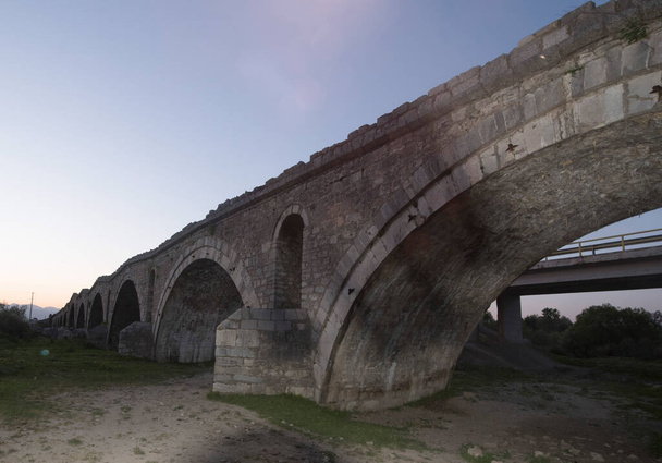 een stenen brug als een structuur die natuurlijke obstakels voor verkeer en vervoer doorkruist - Foto, afbeelding