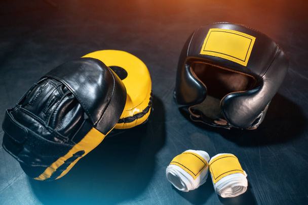 top view of boxing paws, helmet and bandage tape on black background - Photo, Image