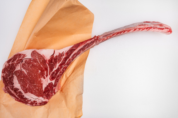 Frisch geschnittenes Tomahawk-Ribeye-Steak mit Fleischerpapier auf der Fleischtheke - Foto, Bild
