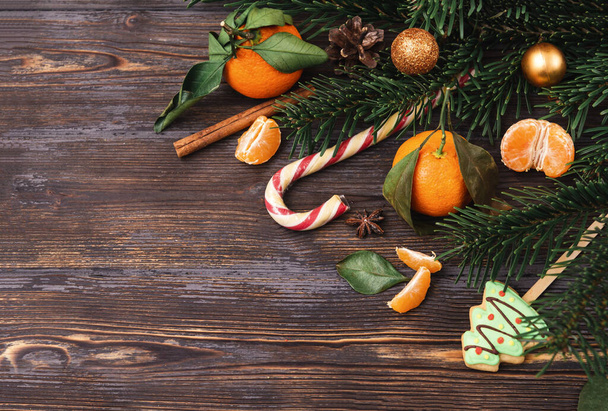 Lollipop,  tangerine,   spruce branch, Golden Christmas balls on a dark wooden background - Foto, Imagen