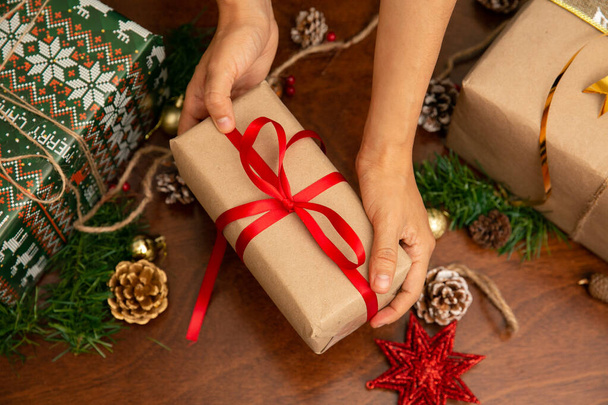 Les mains d'une femme tenant un cadeau de Noël. Le cadeau a un ruban rouge et une étoile - Photo, image