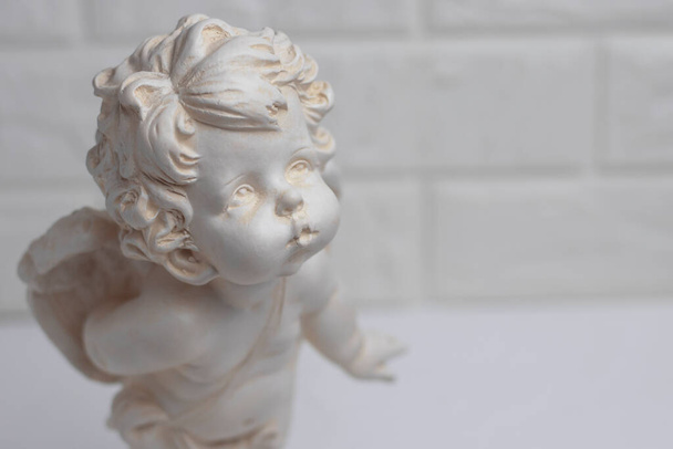 White plaster figurine of an angel on a brick wall background. Decorations in the interior. - Photo, Image