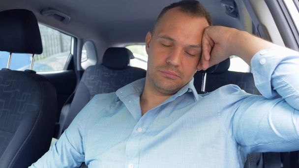 a portrait of a tired man in a car who falls asleep at the wheel - Foto, Imagen