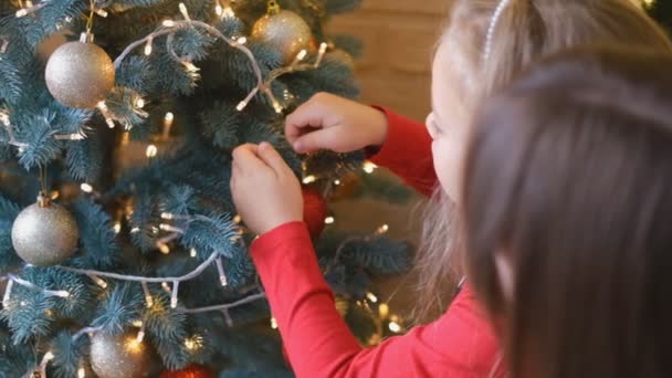 Madre e figlia decorano insieme l'albero di Natale. Genitorialità tradizionale. - Filmati, video