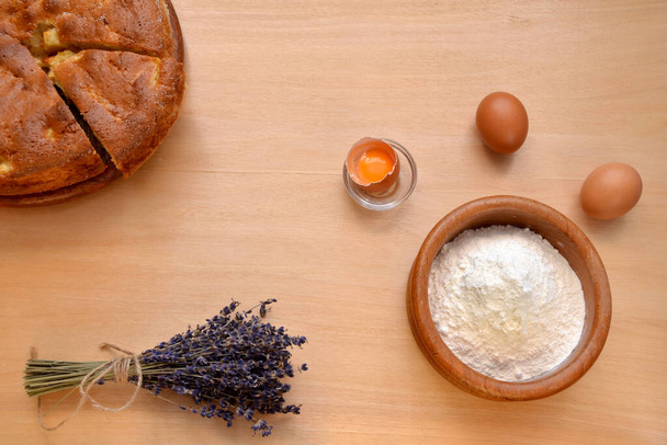 інгредієнти для випічки пирога та яєць та миски з борошном на столі
 - Фото, зображення
