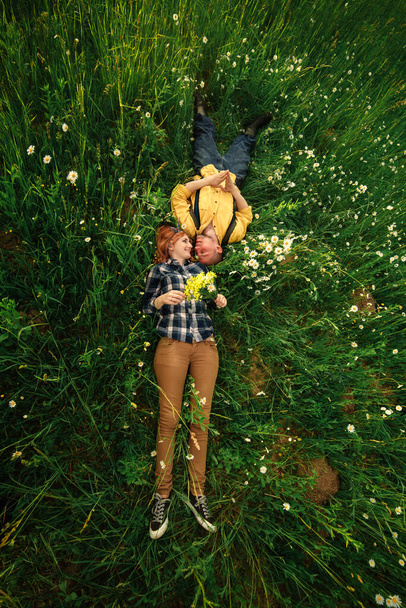 pareja acostada en un campo de flores. Una pareja feliz yace en una flor. Romance, escena emocional y amorosa - Foto, imagen