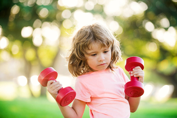 Sporty boy child with dumbbells outdoor. Kids sport, fitness, health and energy, exercises. Healthy lifestyle for little children. - Fotoğraf, Görsel