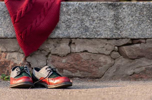 Granit duvarın yanında kırmızı kablo örgü battaniyeli bir çift ayakkabı. - Fotoğraf, Görsel