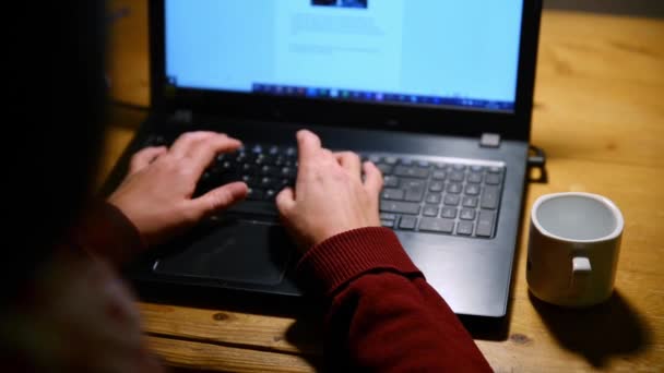 Geceleri dizüstü bilgisayarda çalışan birinin yakın çekimi. Geceleri dizüstü bilgisayarda çalışan bir kadın. Laptop ve kahve kupası ahşap bir masada.. - Video, Çekim